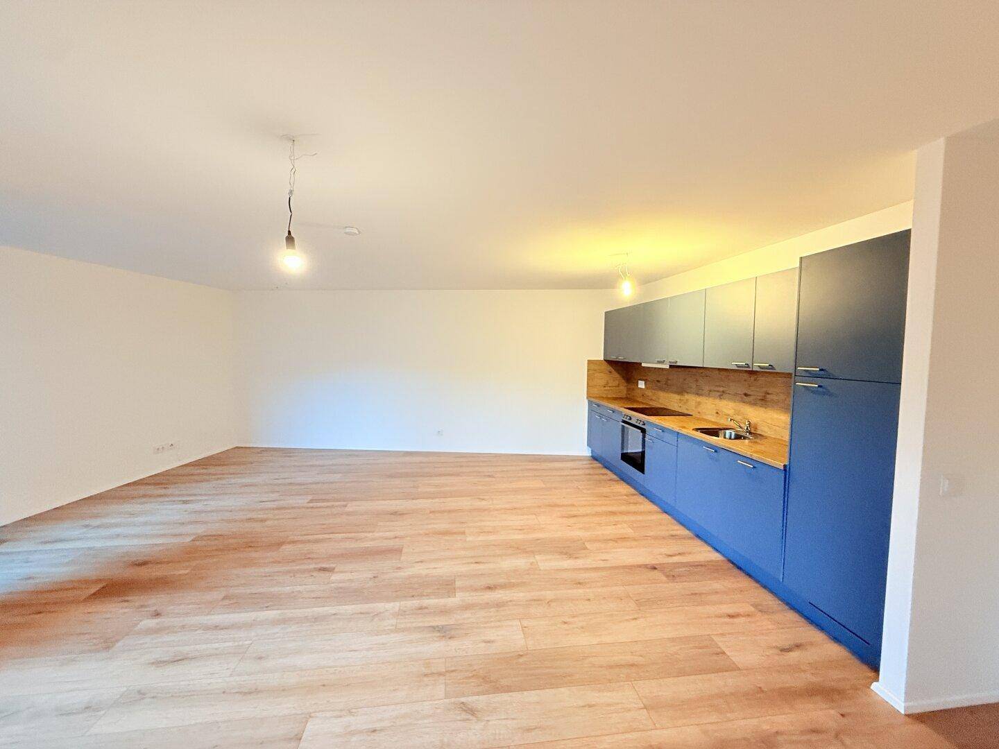Heller Wohnbereich mit integrierter Küche und modernem Laminatboden.