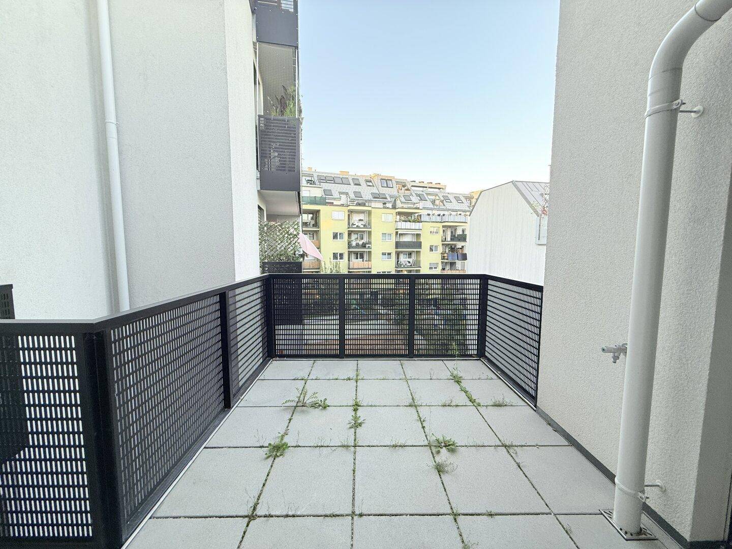 Geräumiger Balkon mit Fliesenboden und Blick auf die umliegenden Gebäude.