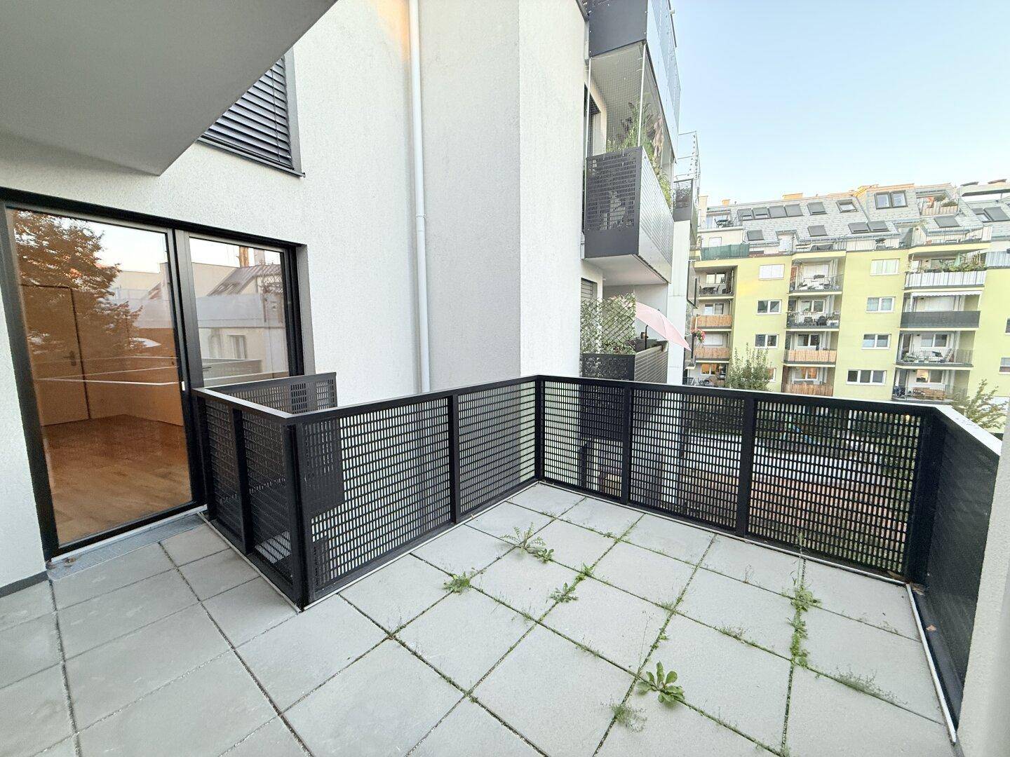 Großer Balkon mit Fliesenboden und Zugang zum Innenraum.
