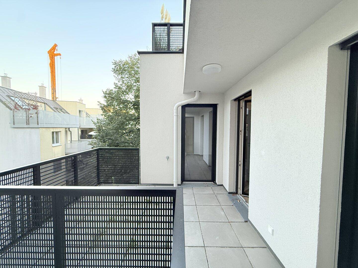 Langer Balkon mit Fliesenboden und Blick auf die Umgebung.