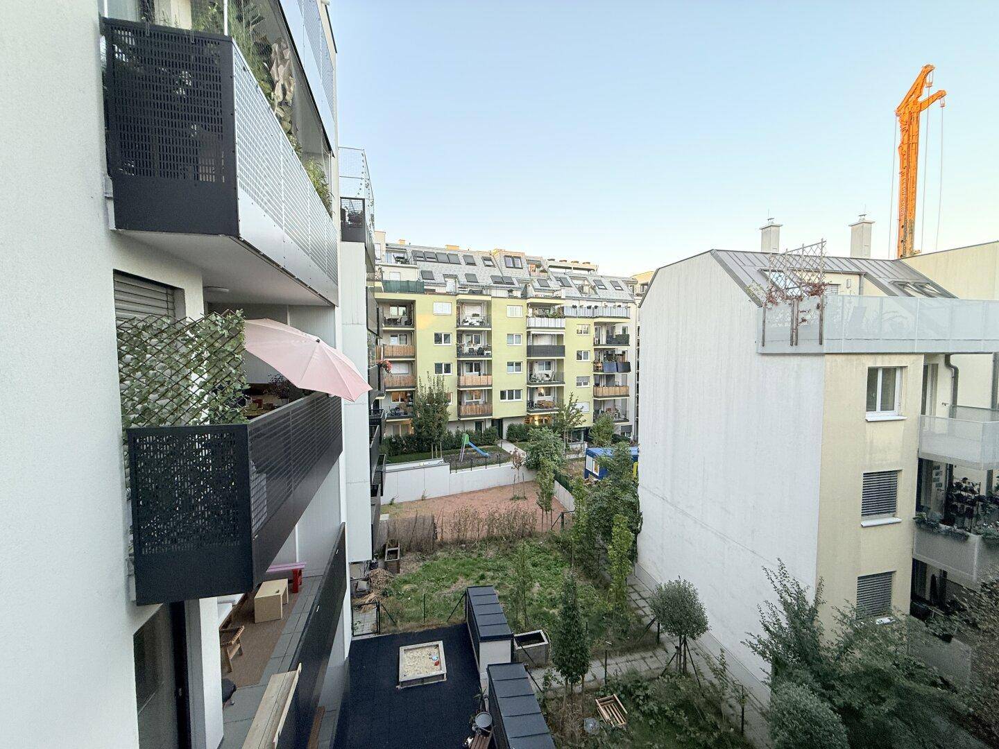 Blick von einem Balkon auf die umliegenden Wohngebäude und einen Innenhof.