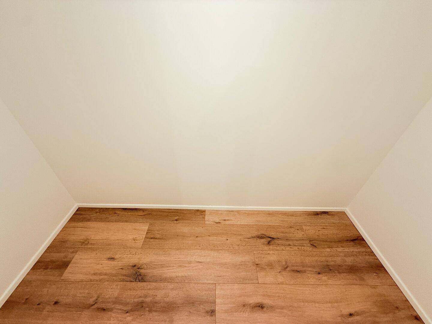 Dachbodenraum mit schrägen Wänden und hellem Laminatboden.