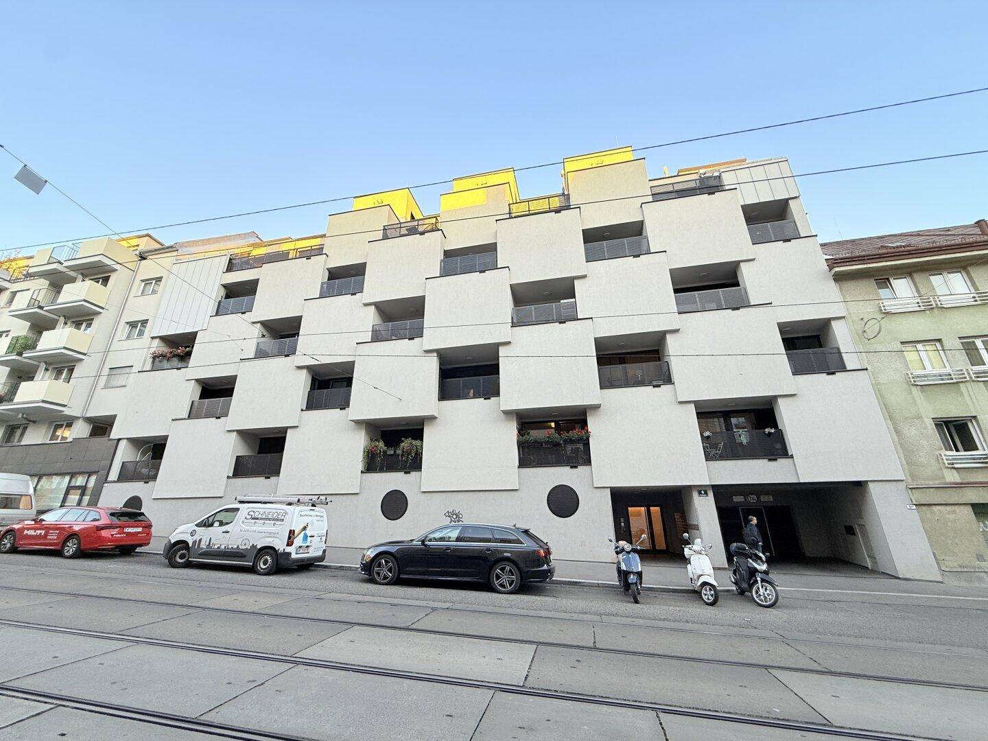 Moderne Wohnhausfassade mit gestaffelten Balkonen und klaren Linien in urbaner Umgebung.