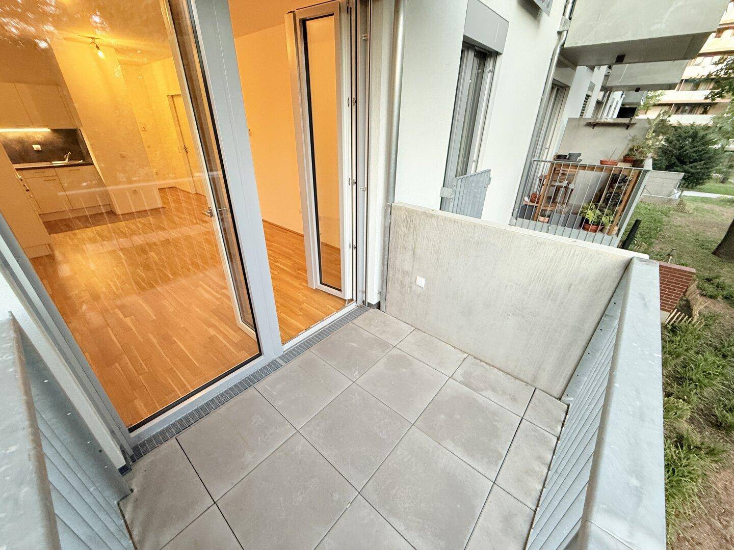 Balkon mit Fliesenboden und Blick zurück in den hellen Wohnbereich der Wohnung.