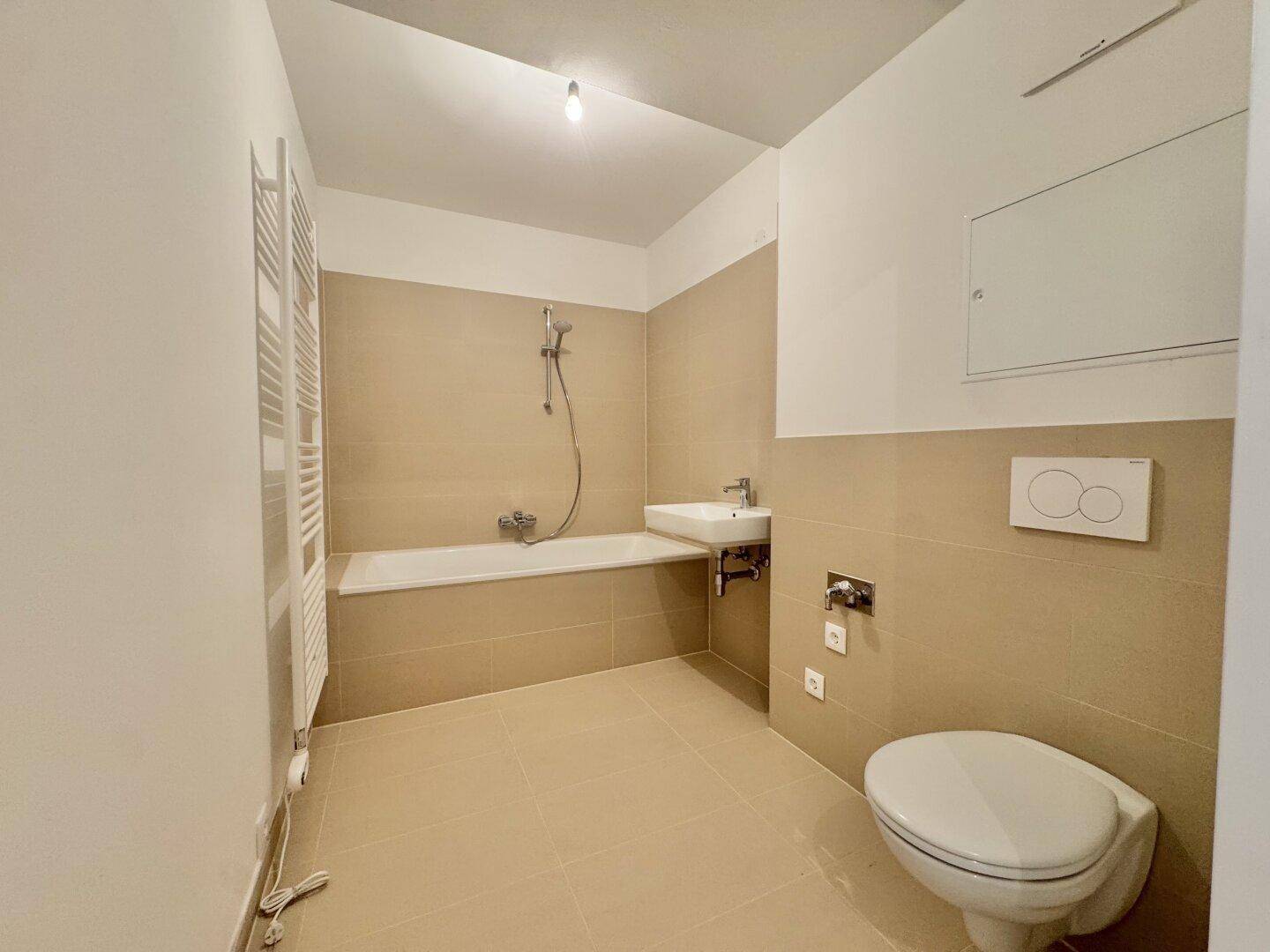Modernes Badezimmer mit Badewanne, WC, Waschbecken und beheiztem Handtuchhalter.