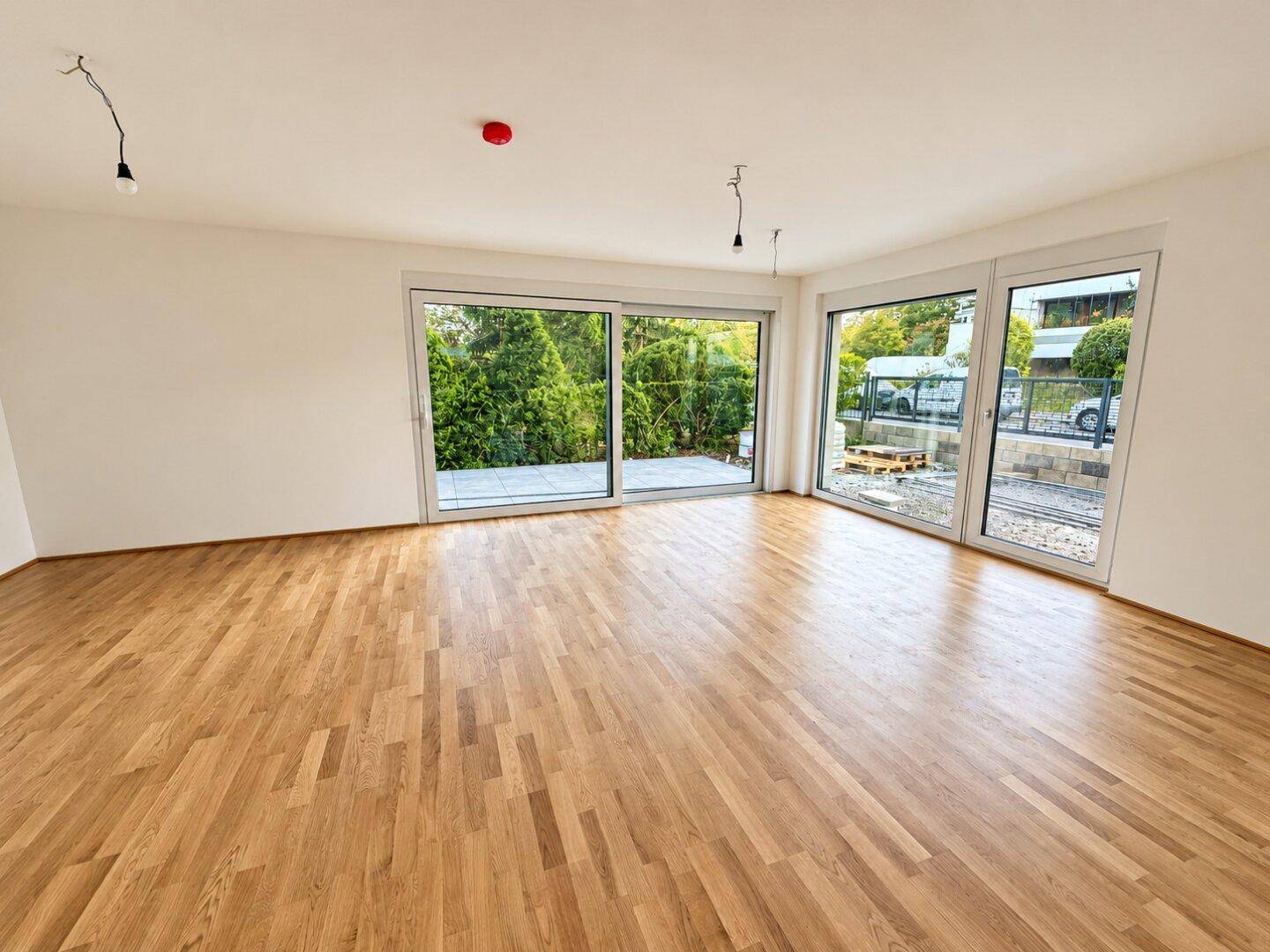 Lichtdurchfluteter Wohnbereich mit Parkettboden und großen Schiebetüren, die zu einer Terrasse führen.