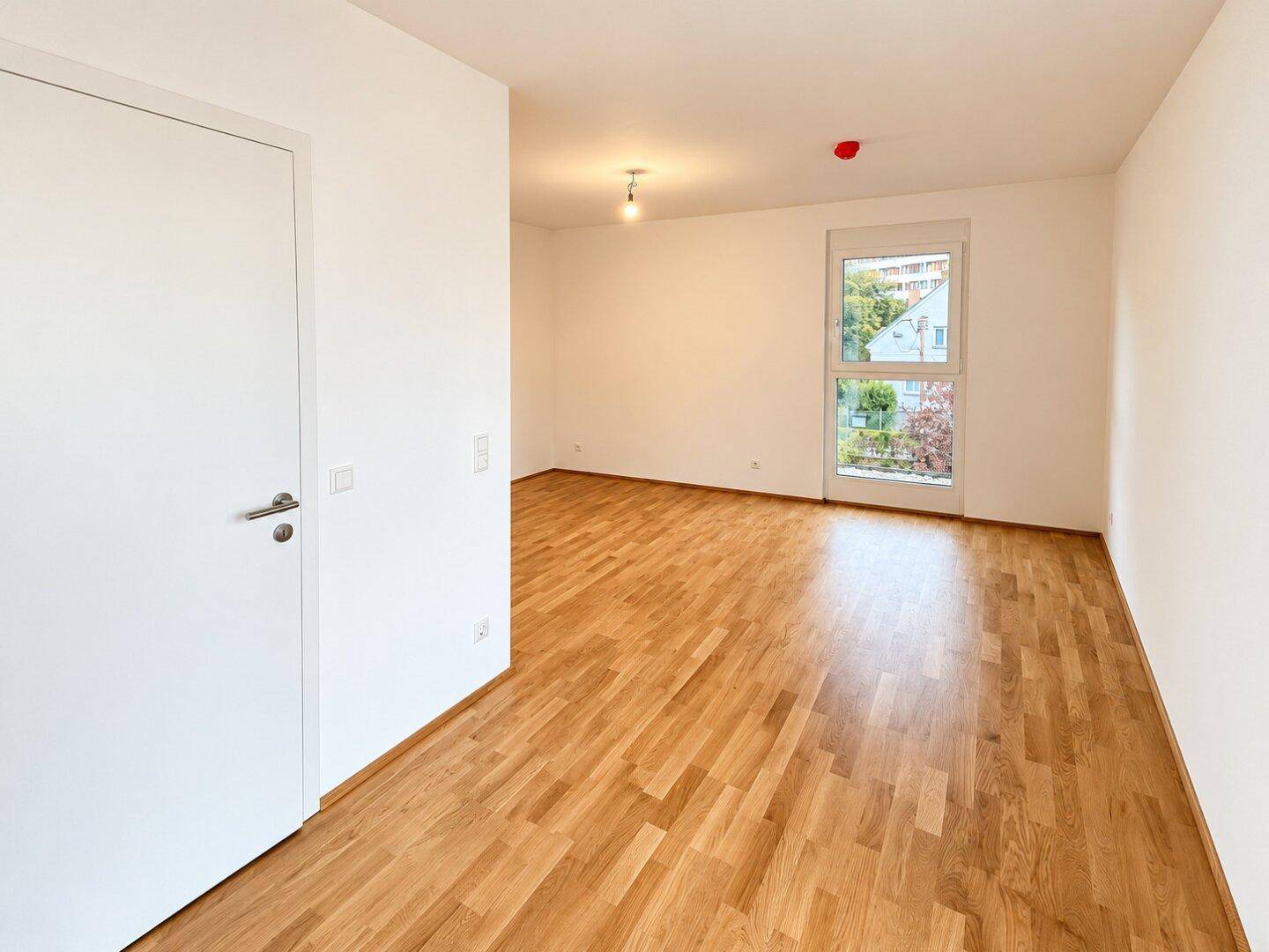 Heller Flur mit Parkettboden und weißer Tür, der zu weiteren Räumen der Wohnung führt.