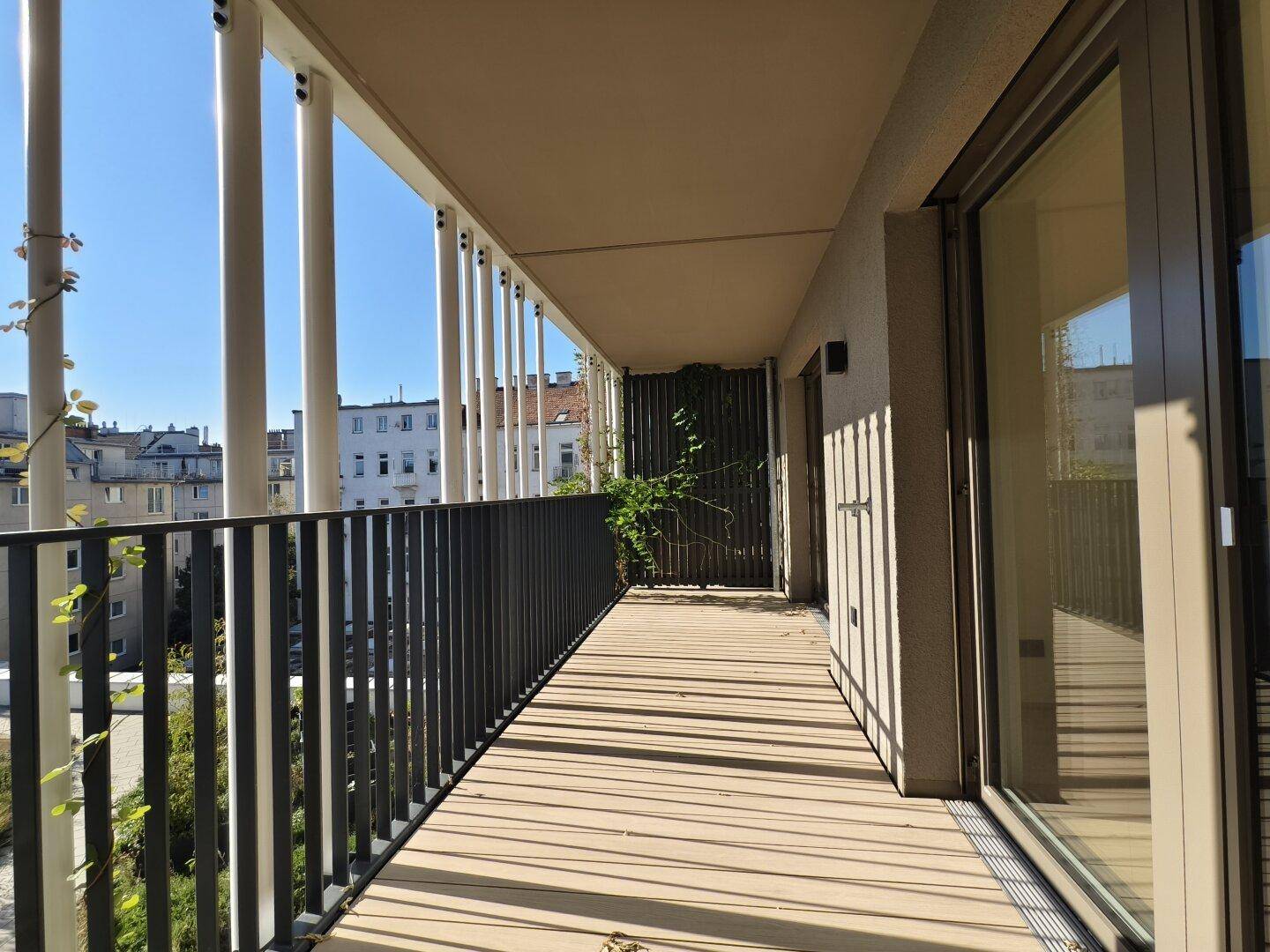 Langer Balkon mit Holzboden und moderner Balustrade, bietet viel Sonnenlicht und Ausblick.