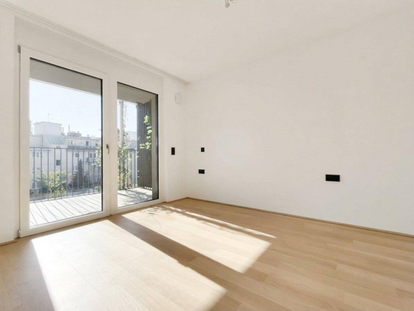 Heller Raum mit Parkettboden und Zugang zum Balkon, bietet viel Tageslicht und Flexibilität.