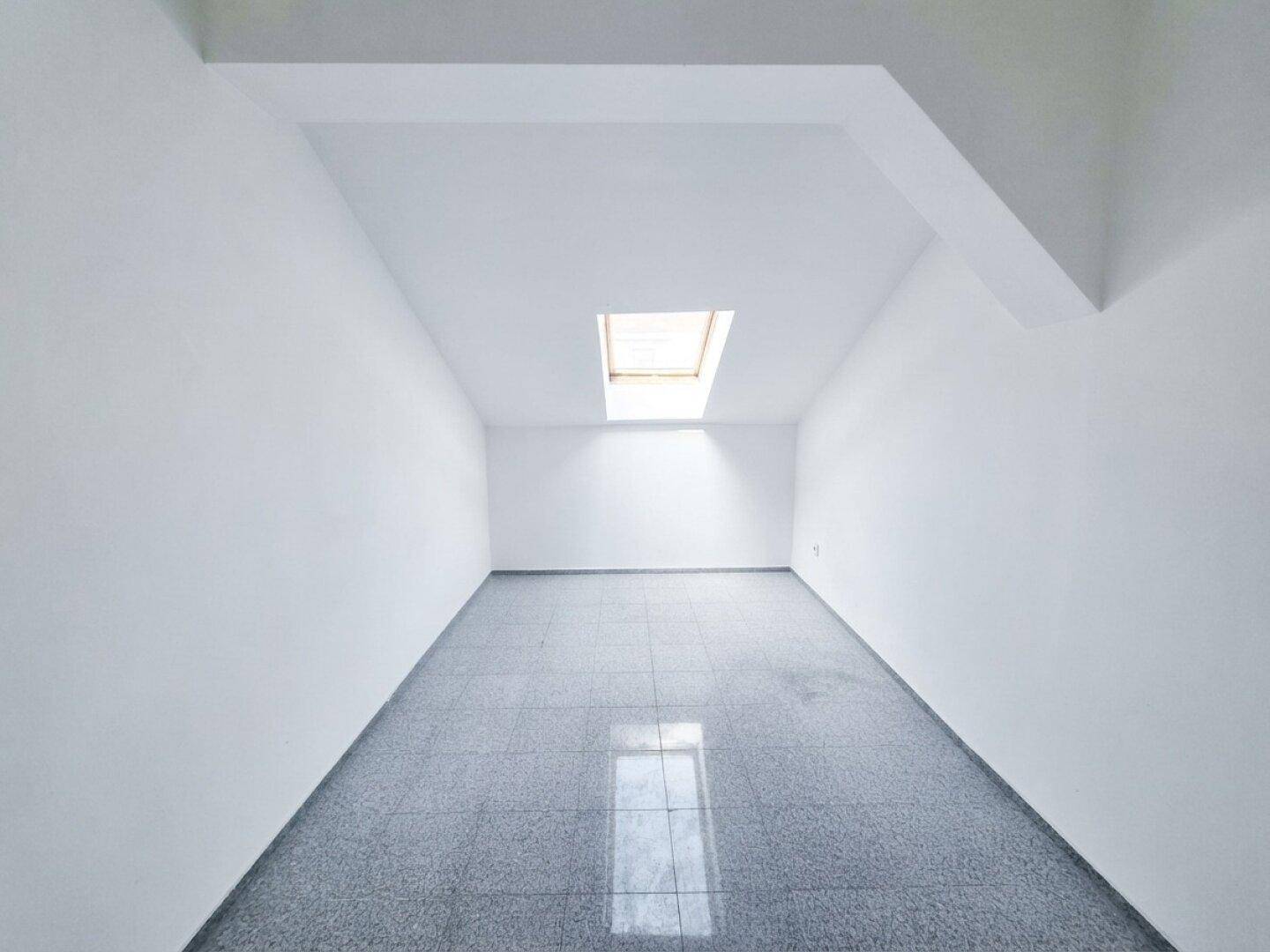 Heller, leerer Raum mit einem Dachfenster und glänzendem Boden, wartet auf die Gestaltung.