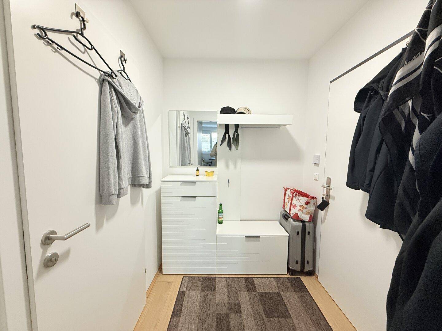 Heller Flur mit Garderobe, Spiegel und Holzboden.