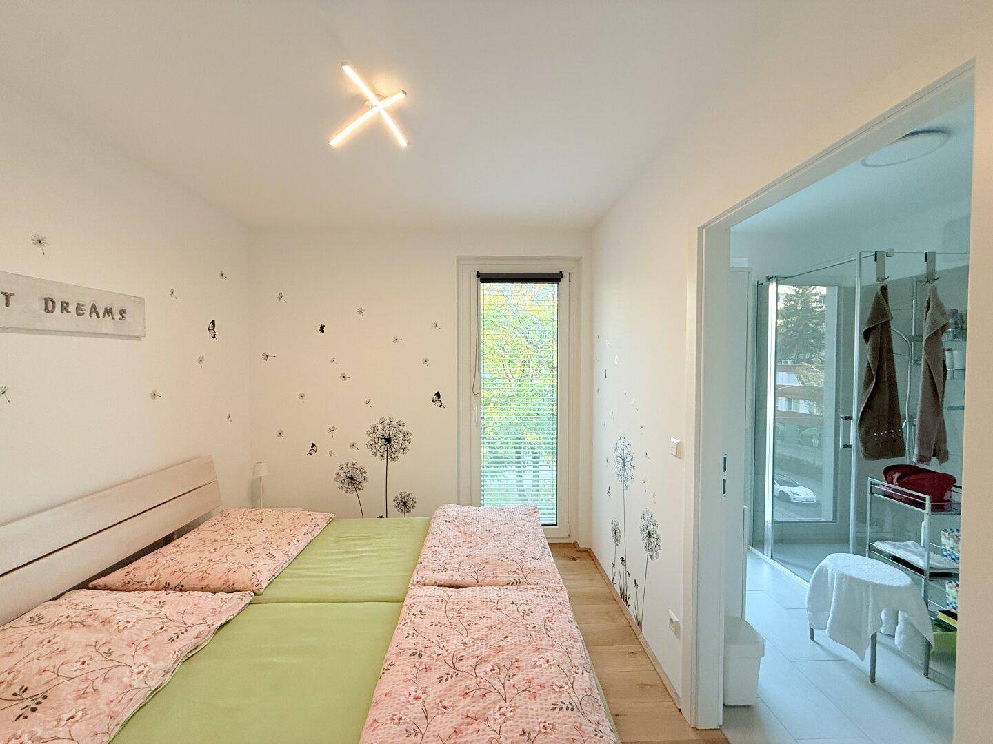 Schlafzimmer mit Doppelbett, Holzboden und Zugang zum Badezimmer.