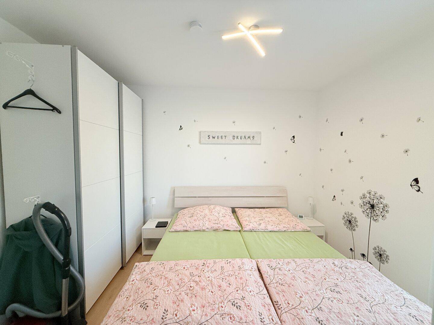 Gemütliches Schlafzimmer mit Doppelbett, Kleiderschrank und heller Einrichtung.