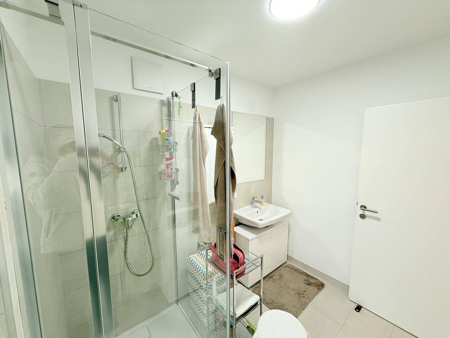 Badezimmer mit Duschkabine, Waschbecken und moderner Ausstattung.