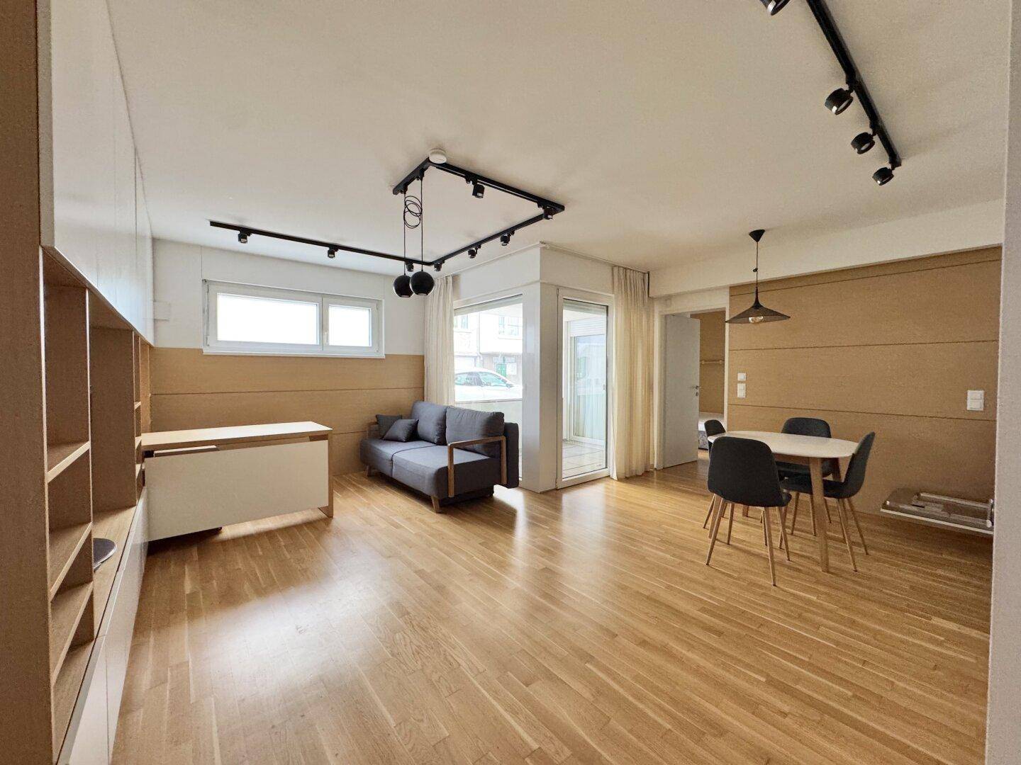 Heller Wohnbereich mit Holzboden, Sofa und Esstisch, offen gestaltet und modern eingerichtet.