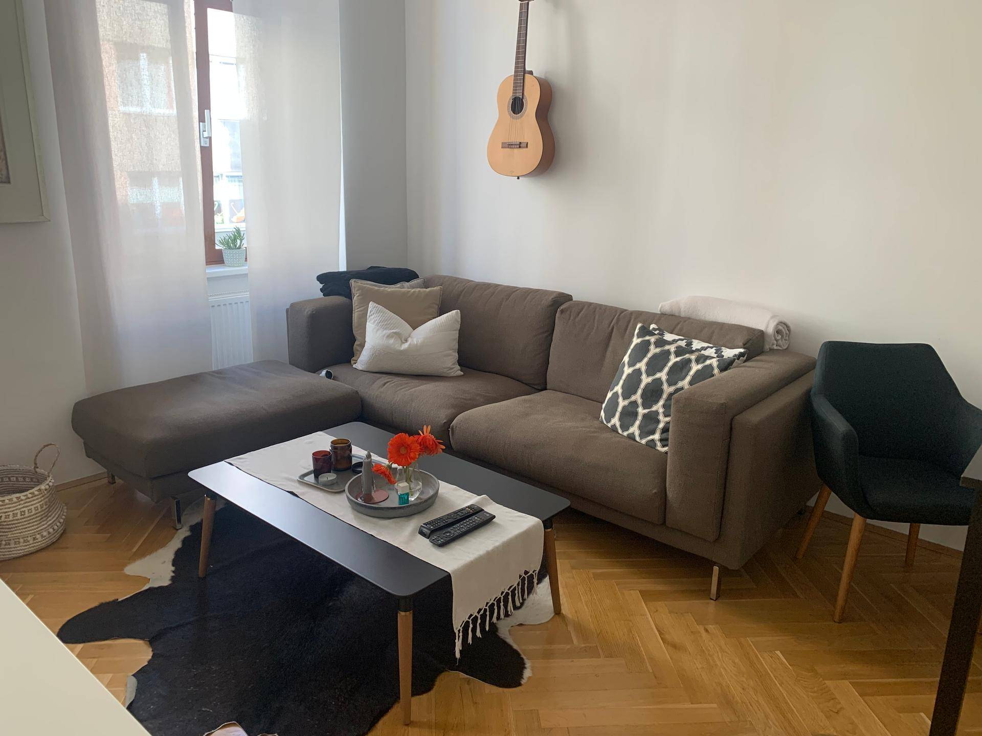 Komfortables Wohnzimmer mit großem Ecksofa, Couchtisch und einem Fenster, das viel Licht hereinlässt.