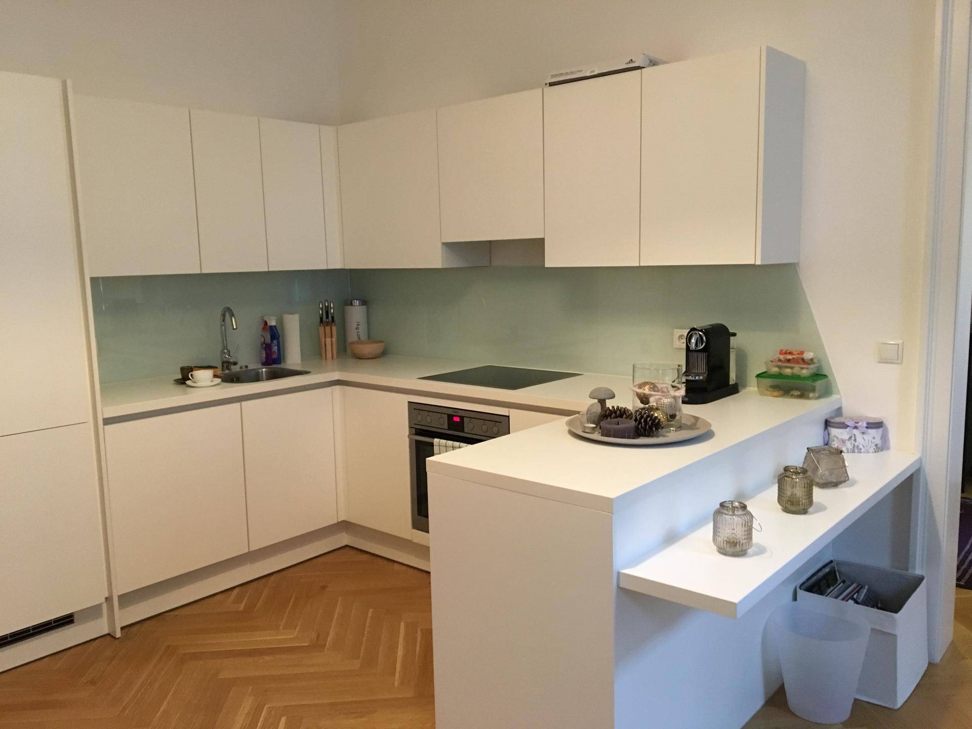 Stilvolle weiße Küche mit modernen Geräten und einer eleganten Theke, dekoriert für eine gemütliche Atmosphäre.