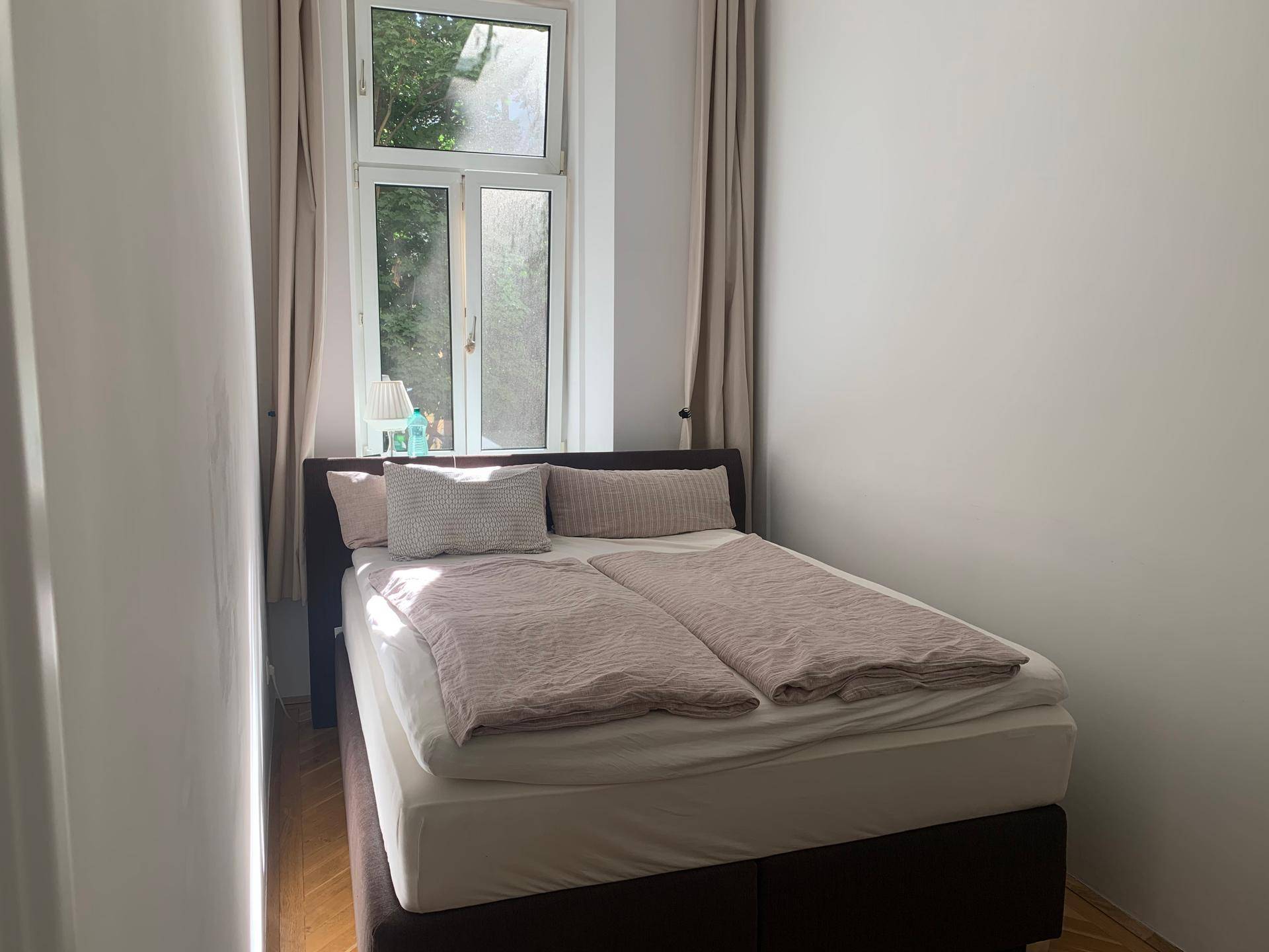 Ruhiges Schlafzimmer mit Doppelbett und einem Fenster, das eine grüne Aussicht bietet.