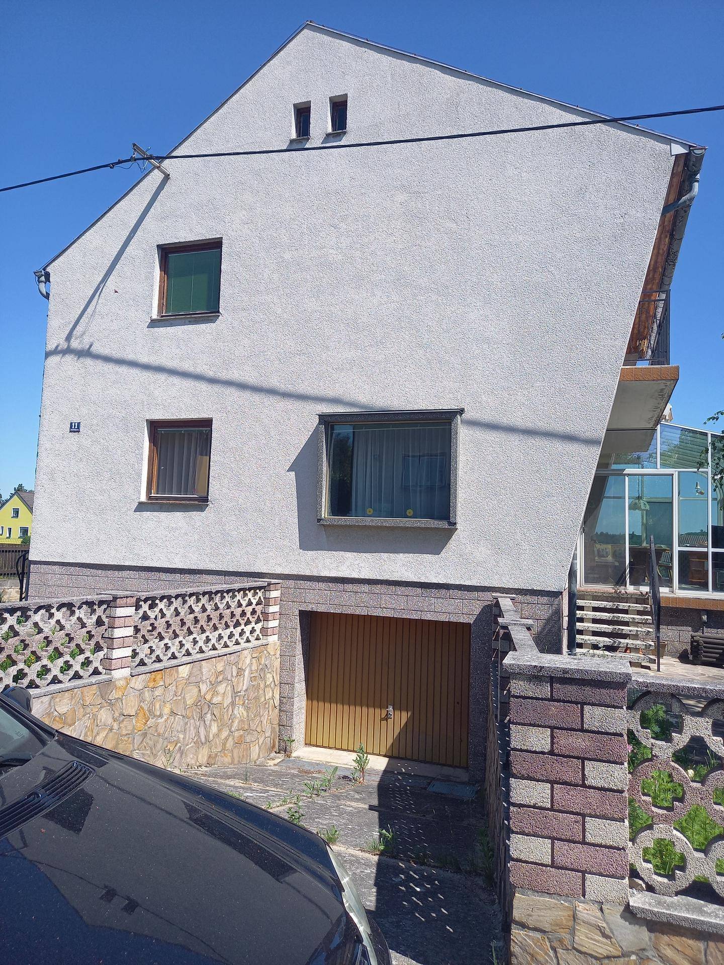Seitenansicht des Hauses mit Garagentor und schräger Dachkonstruktion.