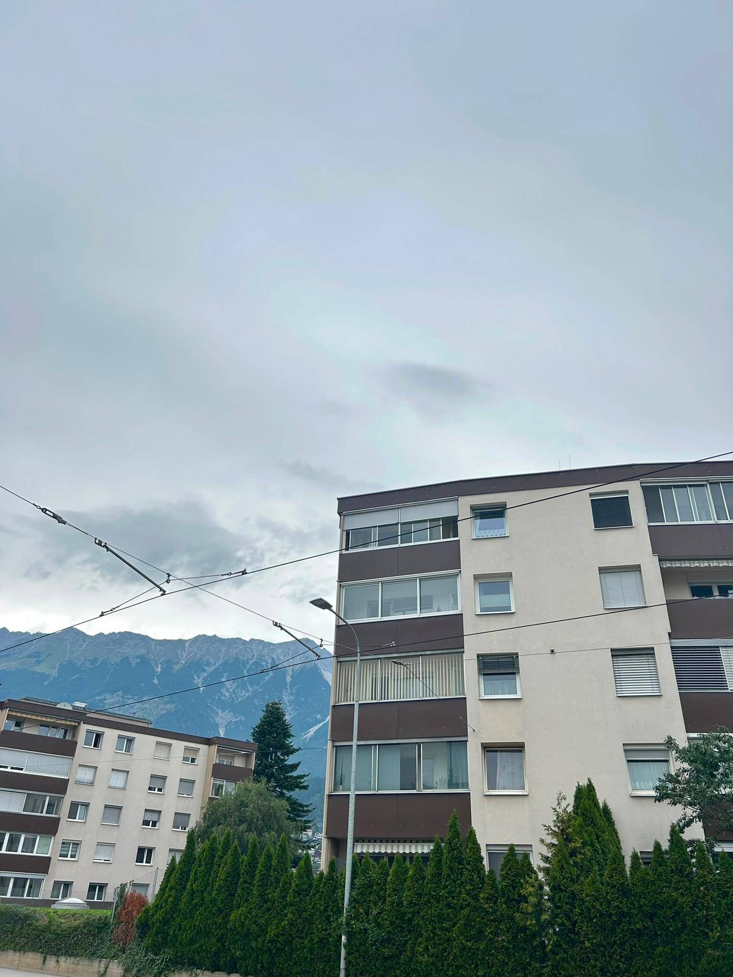 Wohngebäude mit moderner Architektur und Blick auf die umliegende Berglandschaft unter bewölktem Himmel.