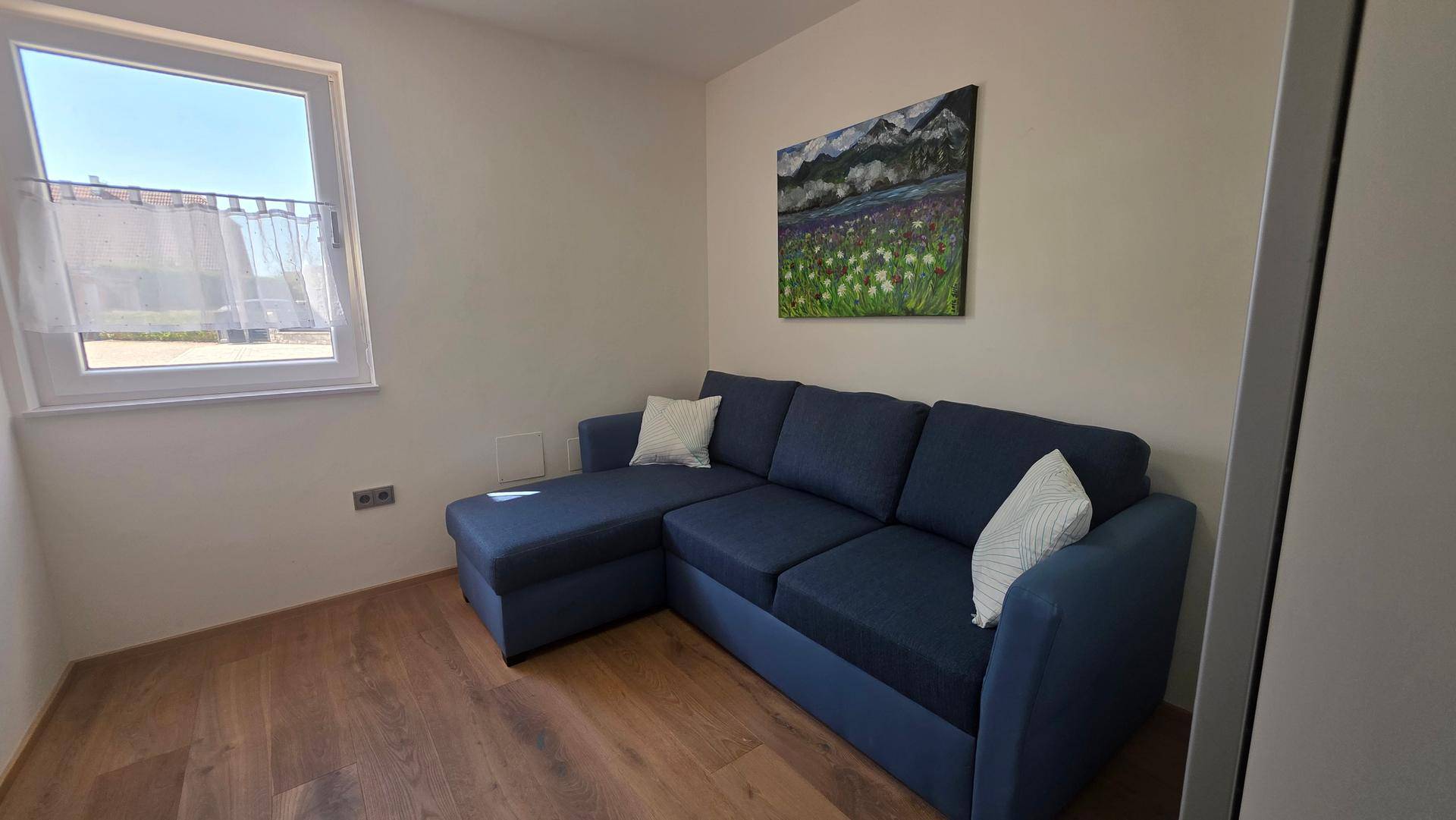 Helles Arbeitszimmer mit blauem Sofa und Fenster, ideal für Home-Office.