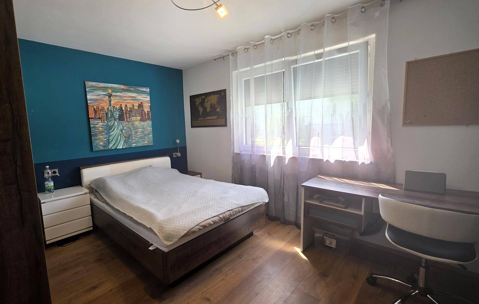 Schlafzimmer mit Doppelbett, Schreibtisch und einer farbigen Akzentwand.