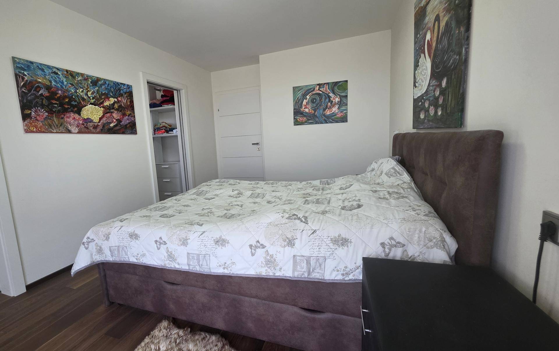 Schlafzimmer mit Doppelbett und begehbarem Kleiderschrank im Hintergrund.