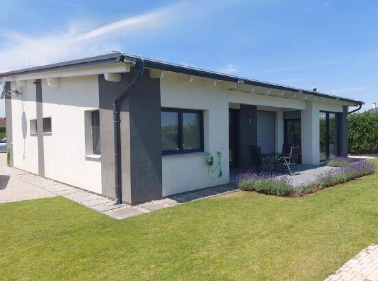 Modernes Einfamilienhaus mit weiß-grauer Fassade, großen Fenstern und einer kleinen Terrasse mit Lavendel.