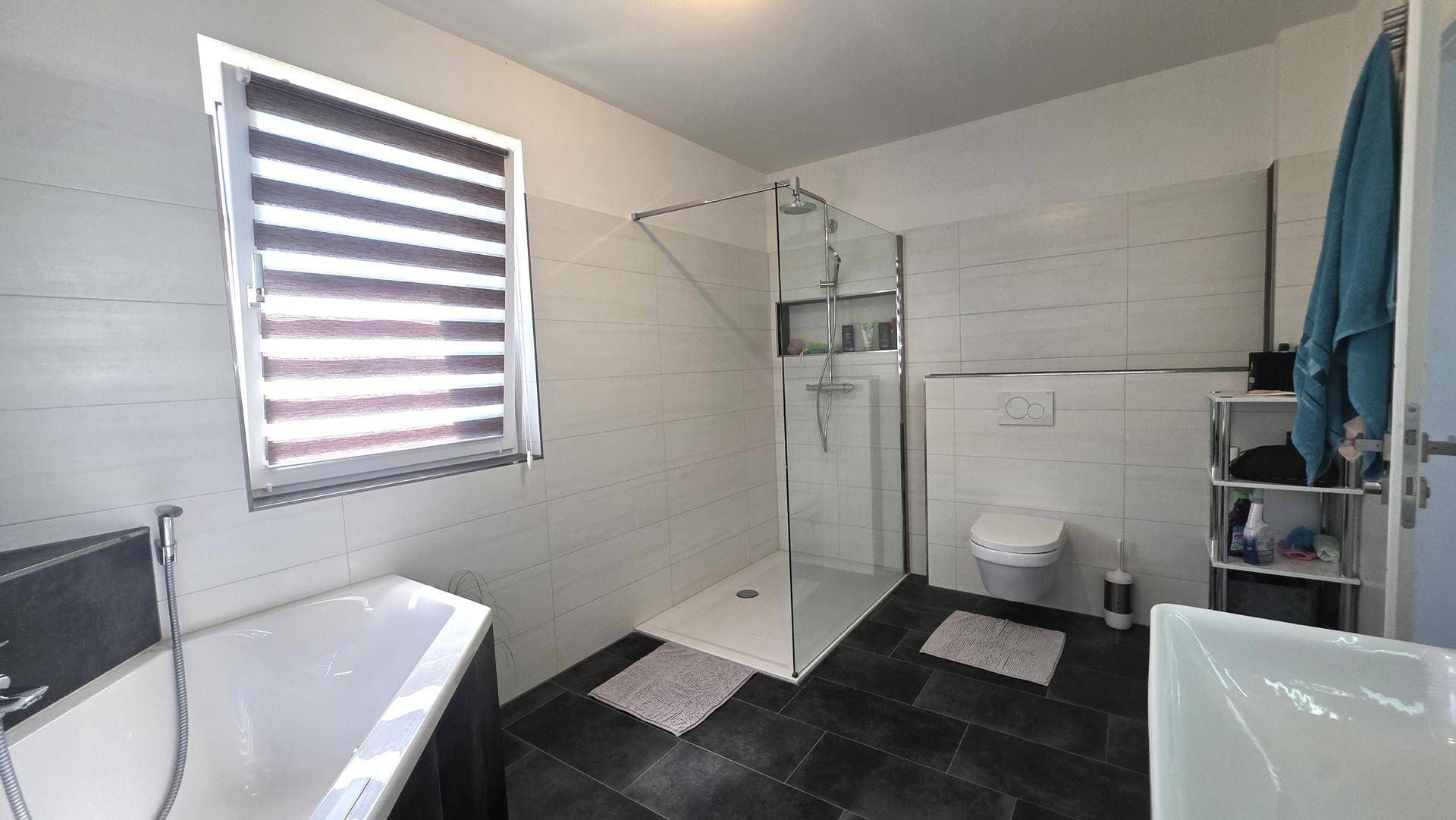 Helles Badezimmer mit ebenerdiger Dusche, Toilette und Eckbadewanne.