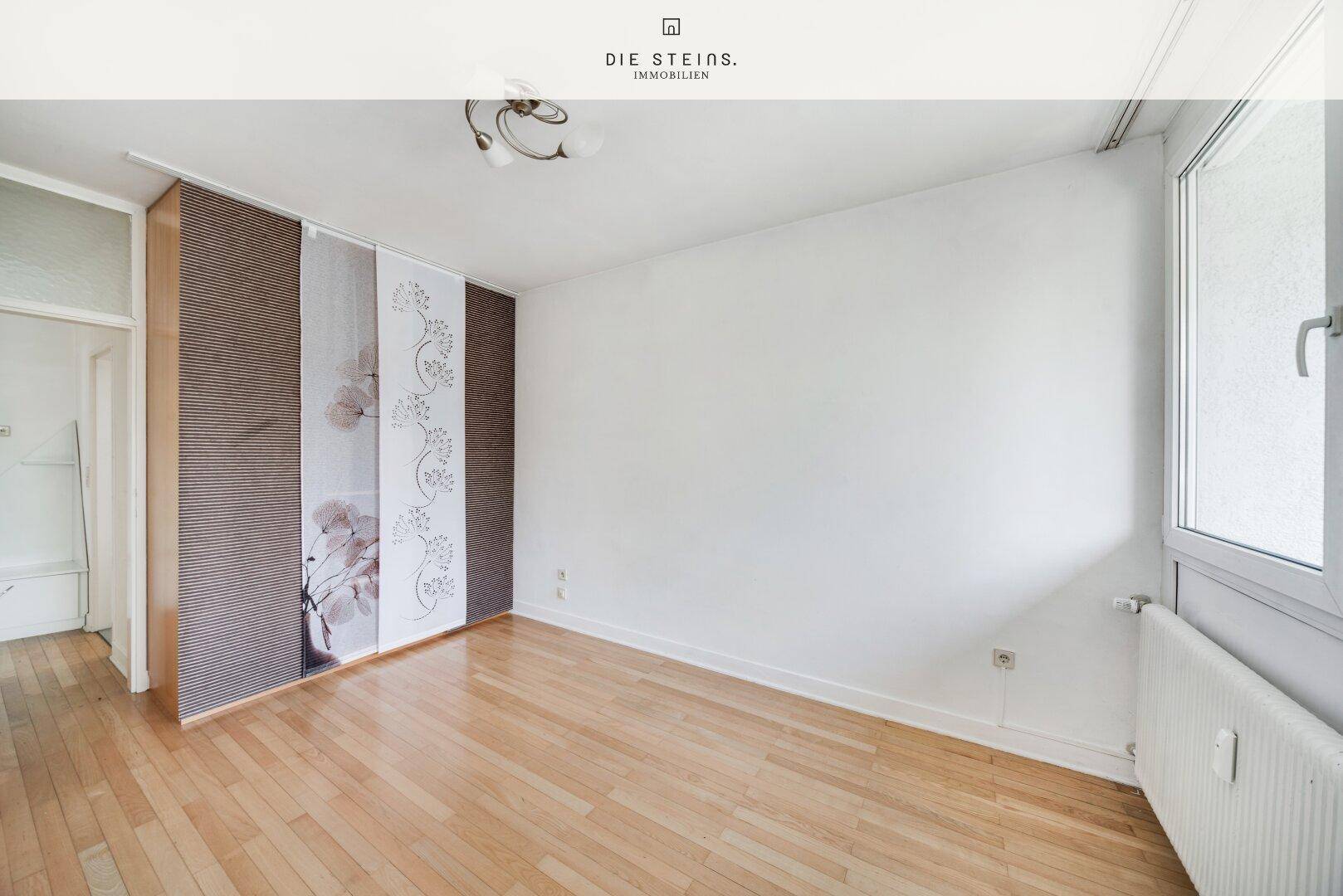 Schlafzimmer mit Parkettboden und dekorativen Schiebevorhängen, bietet Platz für individuelle Einrichtung.