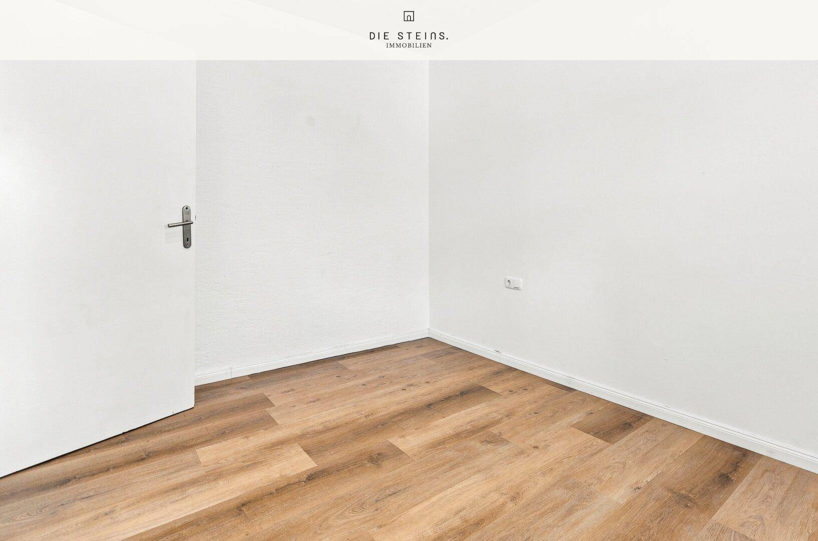 Kleiner, heller Raum mit Laminatboden und weißer Tür, vielseitig nutzbar als Schlaf- oder Arbeitszimmer.