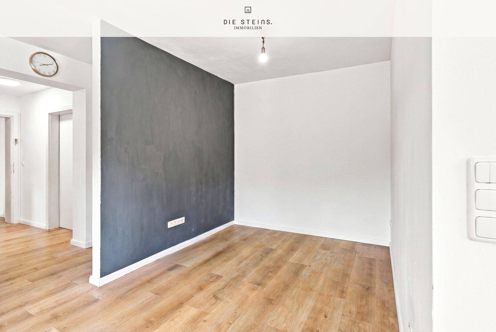 Heller Raum mit Laminatboden und einer dunkelgrauen Akzentwand, ideal für individuelle Gestaltung.