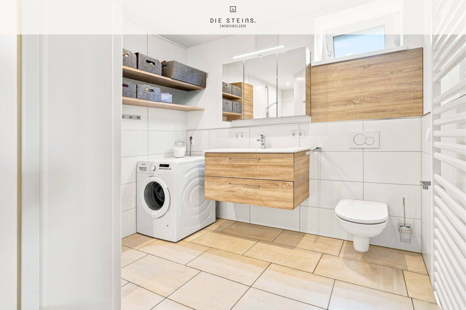 Modernes Badezimmer mit WC, Waschbecken, Waschmaschine und Spiegelschrank.