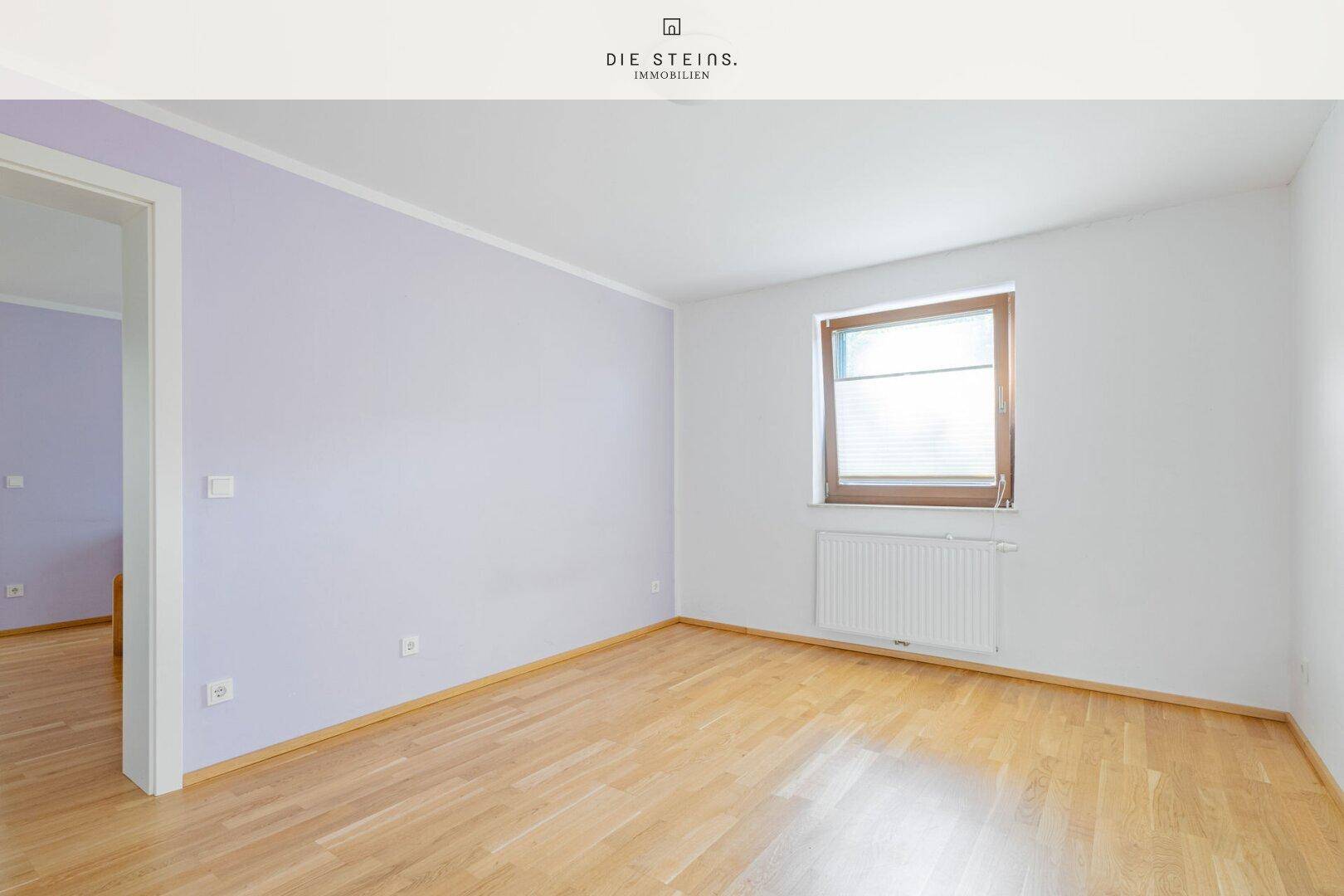 Leeres Schlafzimmer mit hellem Holzboden und einer Wand in zartem Lila.