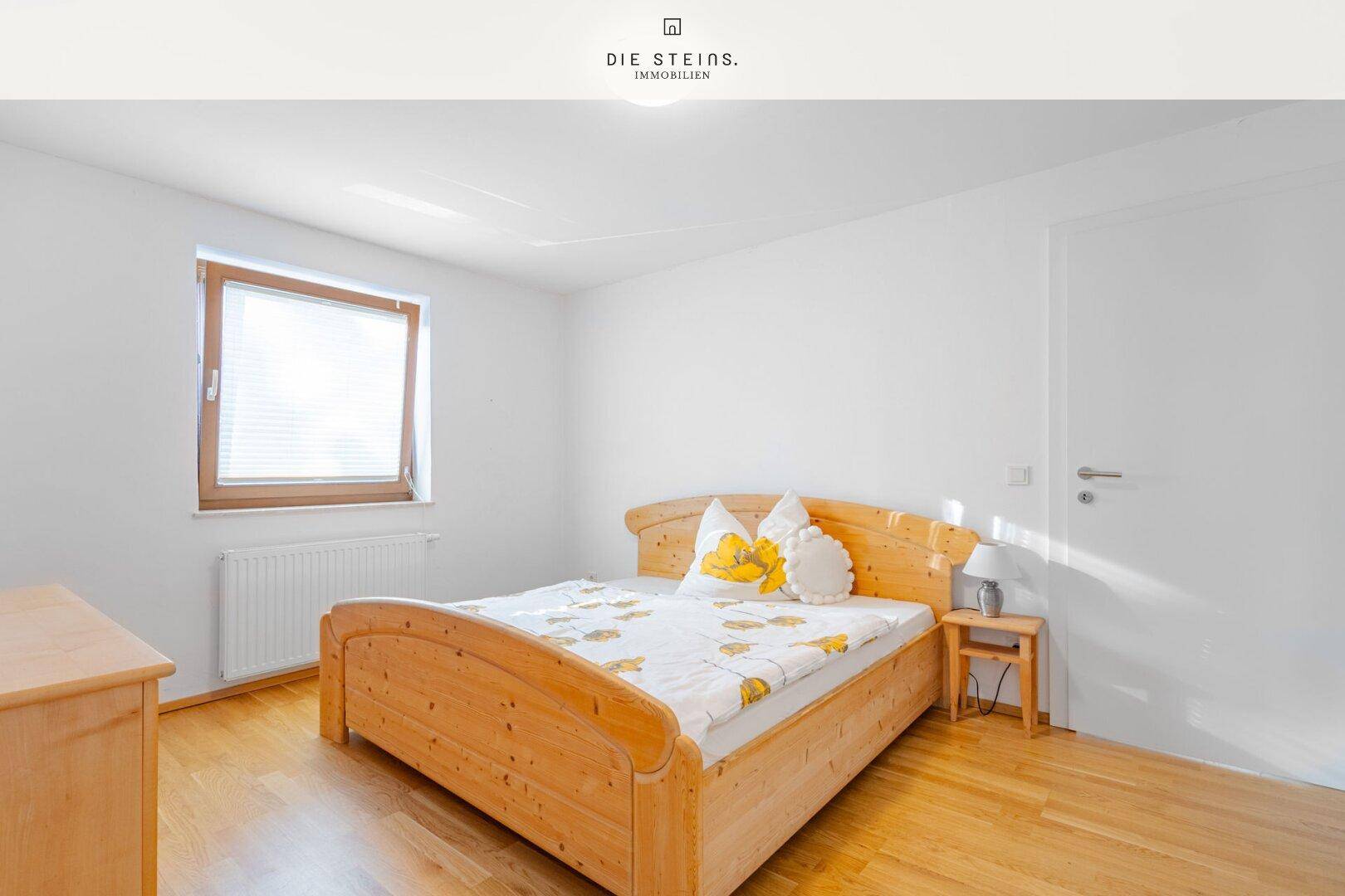 Helles Schlafzimmer mit Doppelbett aus hellem Holz und Parkettboden.