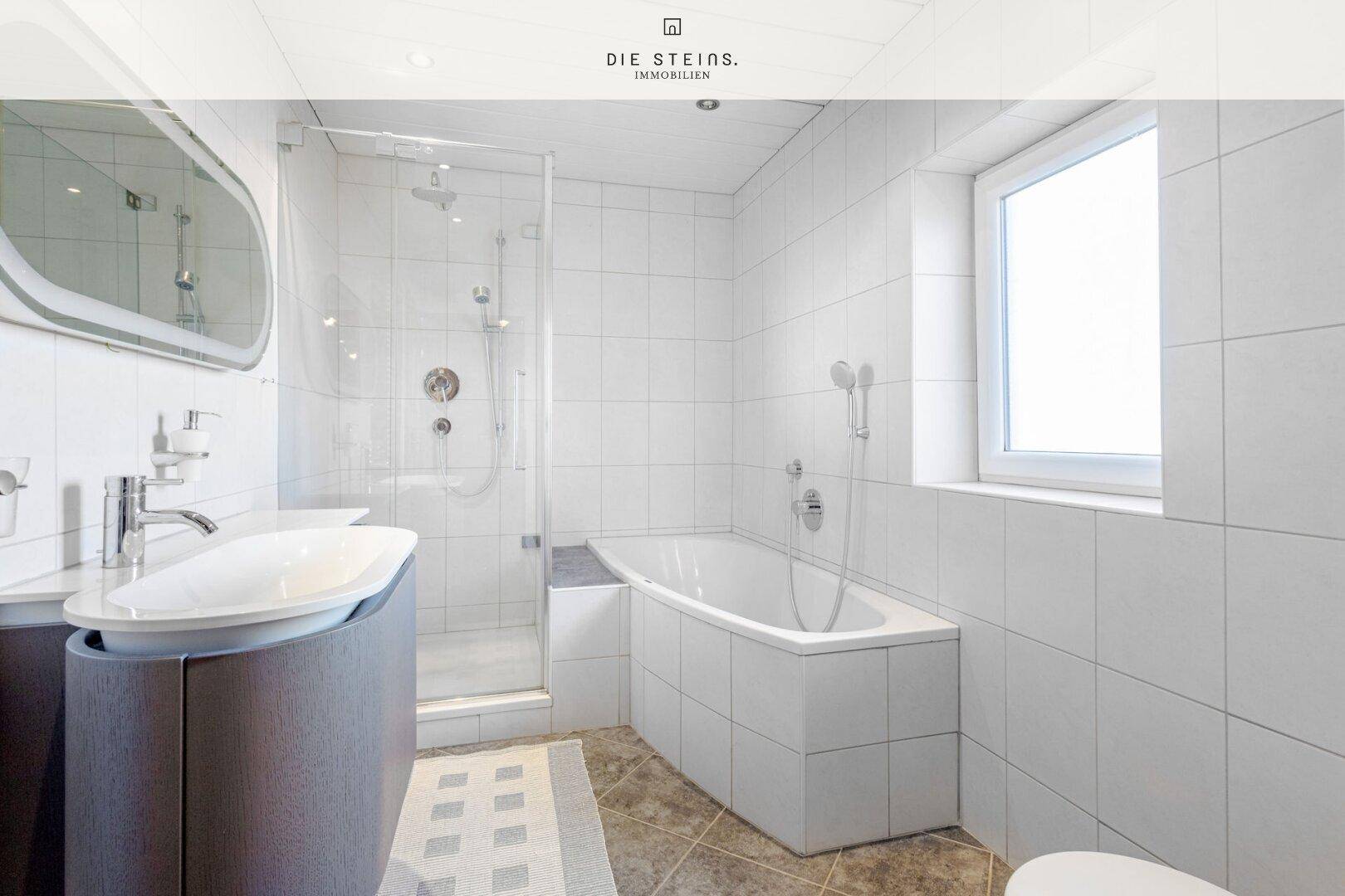 Modernes Badezimmer mit Badewanne, Dusche, Fenster und elegantem Waschtisch.