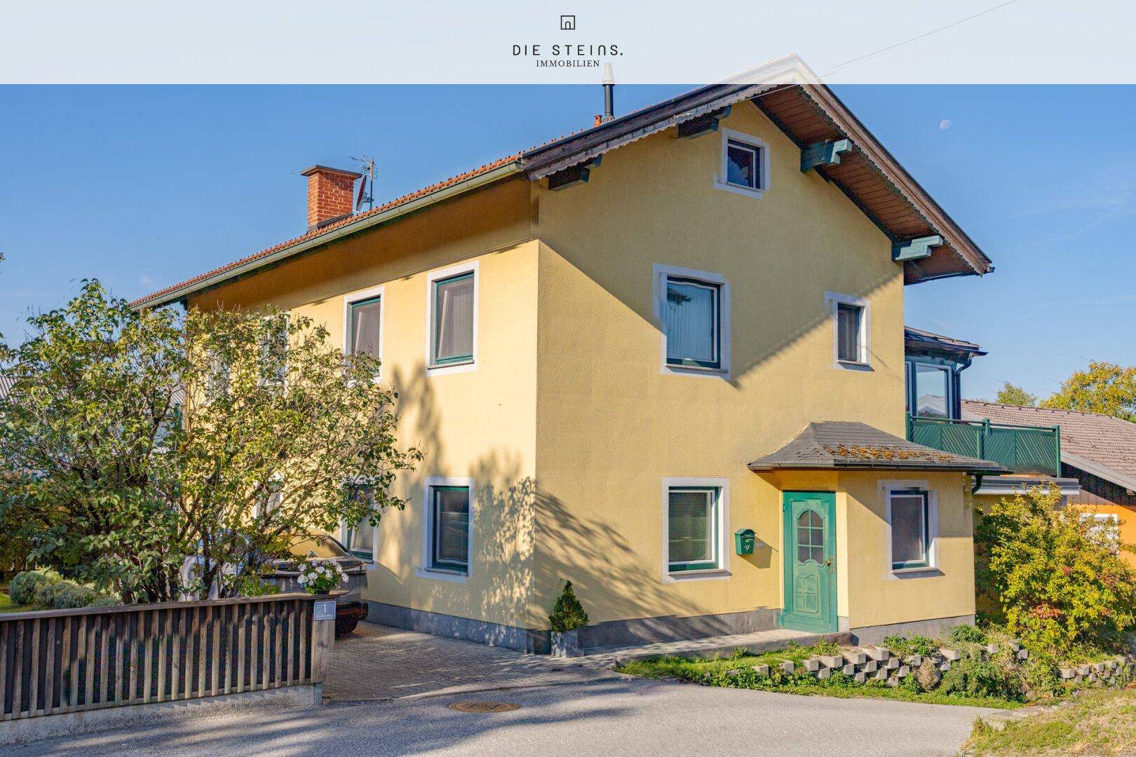 Gelbes Einfamilienhaus mit grüner Eingangstür und gepflegtem Vorgarten.