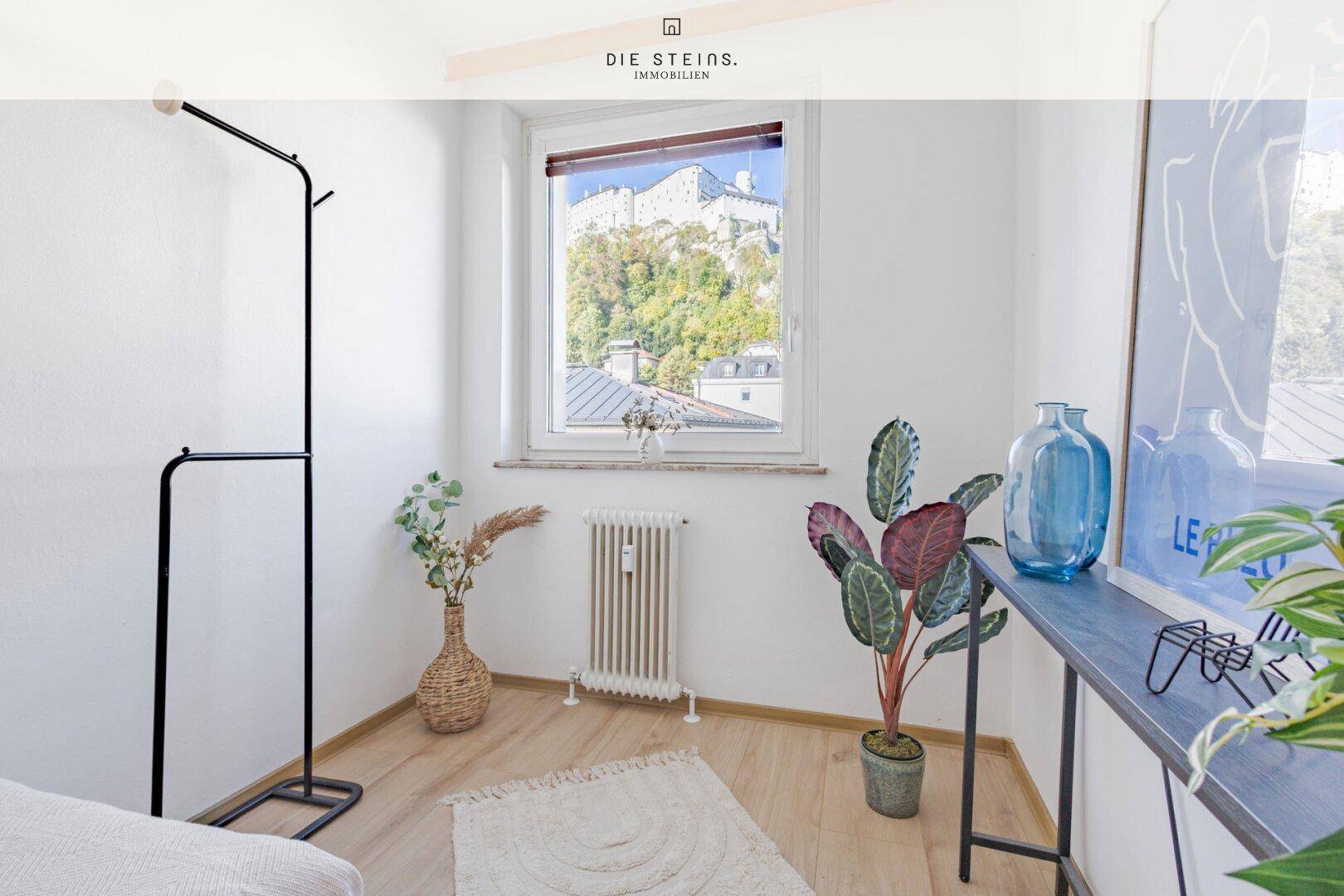 Gemütliches Schlafzimmer mit Holzboden, Fenster und Blick auf die Festung.
