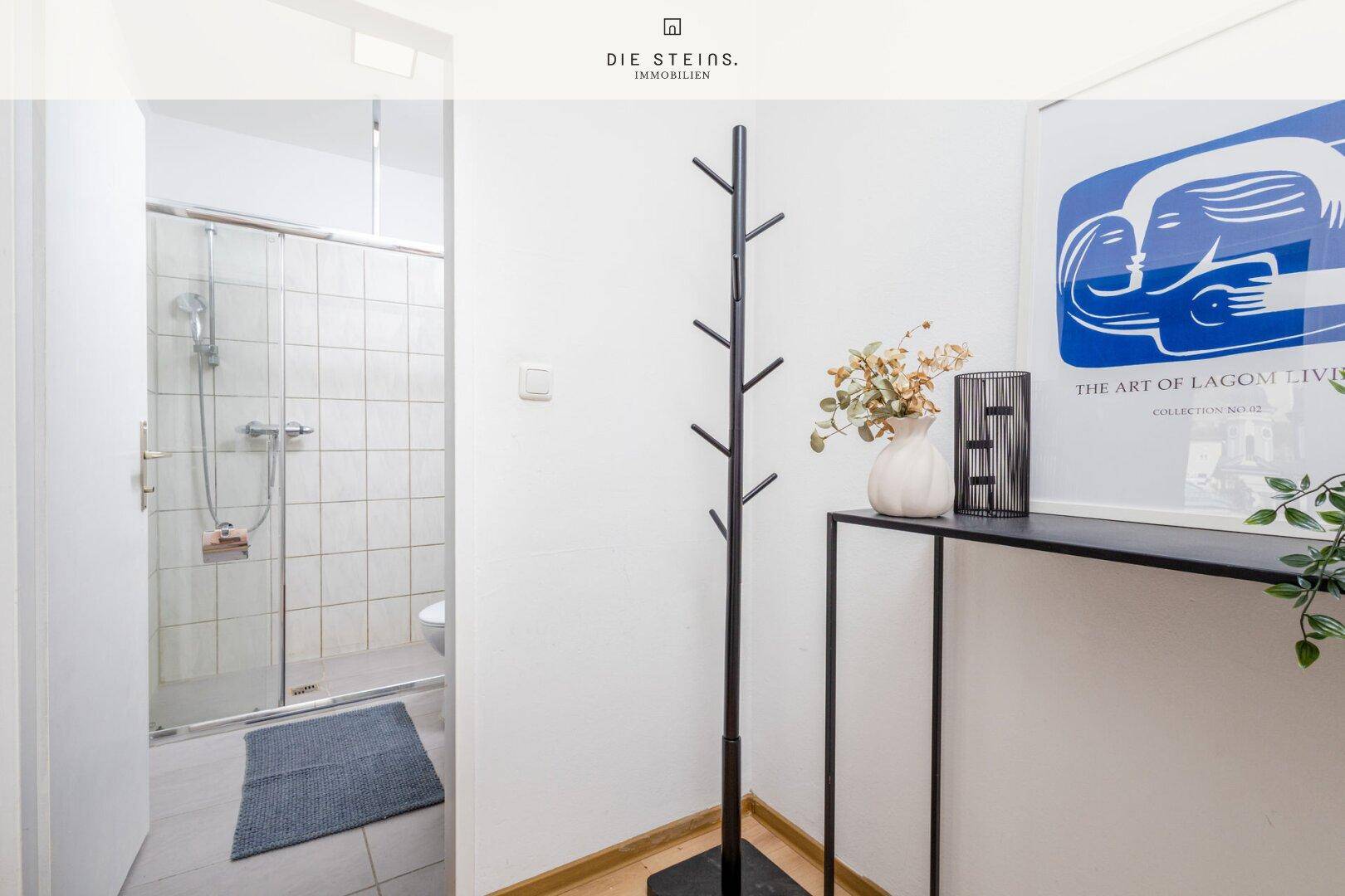 Heller Flur mit Garderobe und direktem Zugang zum Badezimmer.