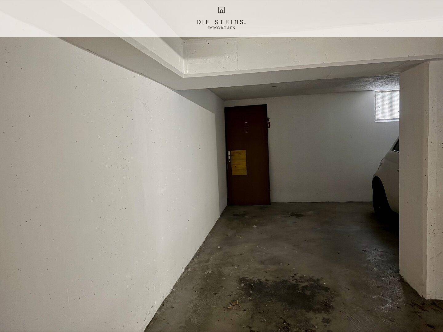 Geräumige Garage mit Betonboden und weiß gestrichenen Wänden, bietet Platz für ein Fahrzeug.