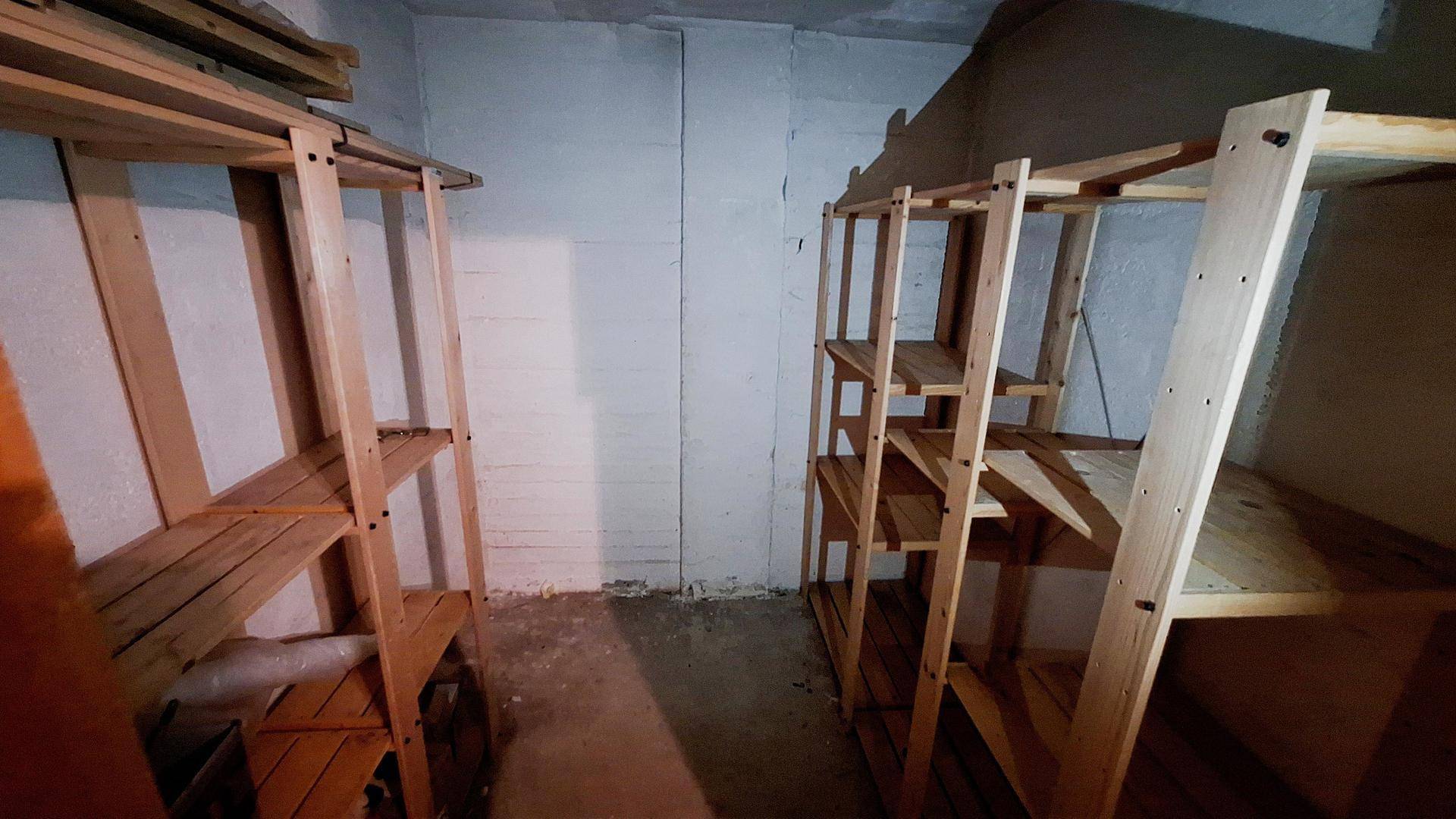 Kellerraum mit Holzregalen und Betonwänden, ideal für zusätzlichen Stauraum.