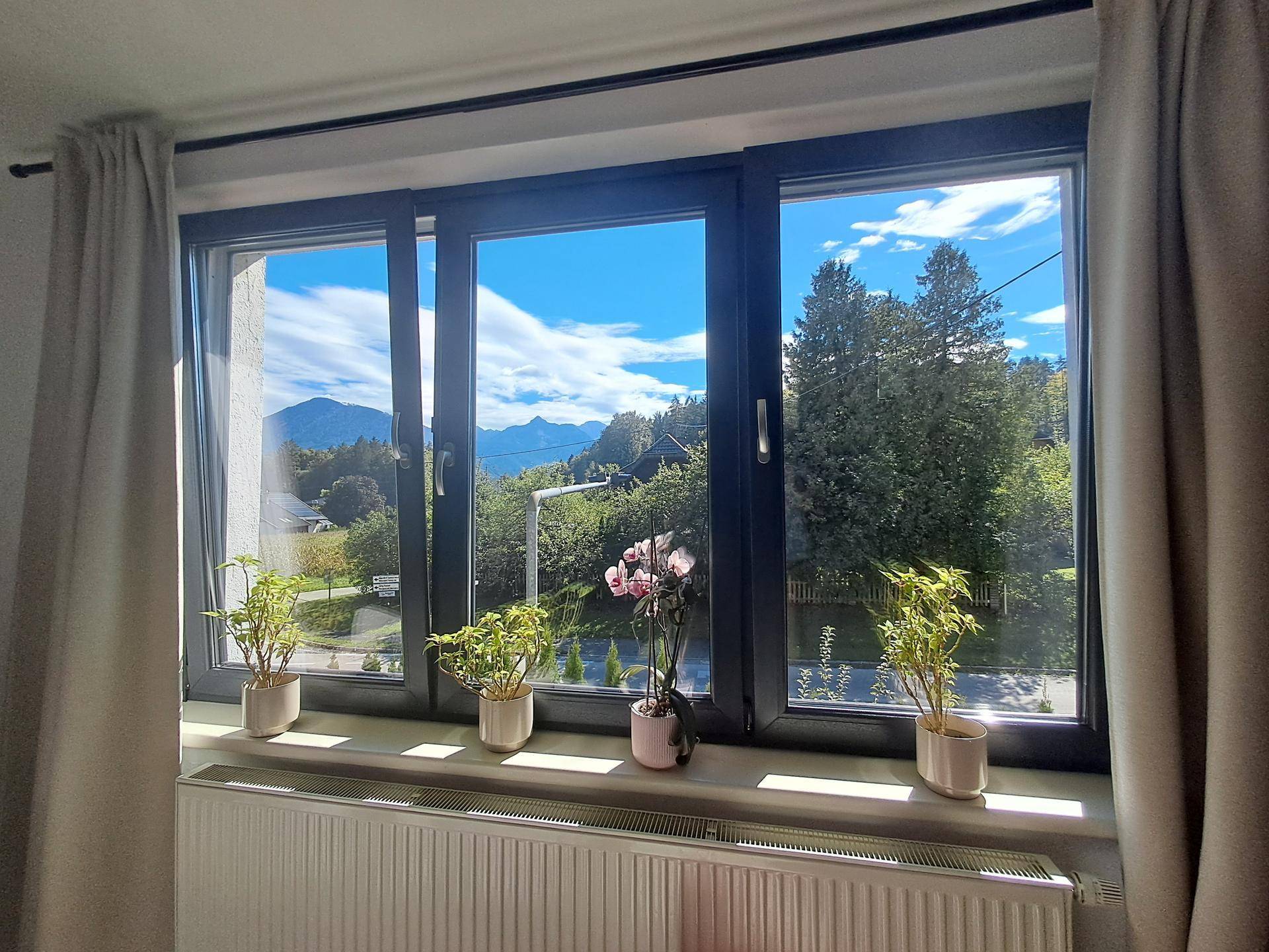 Fenster mit atemberaubendem Blick auf die umliegende Berglandschaft und blauen Himmel.