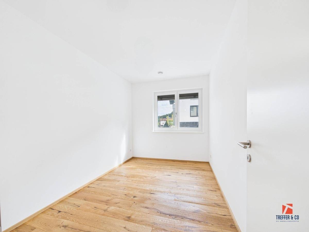 Helles Schlafzimmer mit Holzboden und Fenster, bereit zur individuellen Gestaltung.