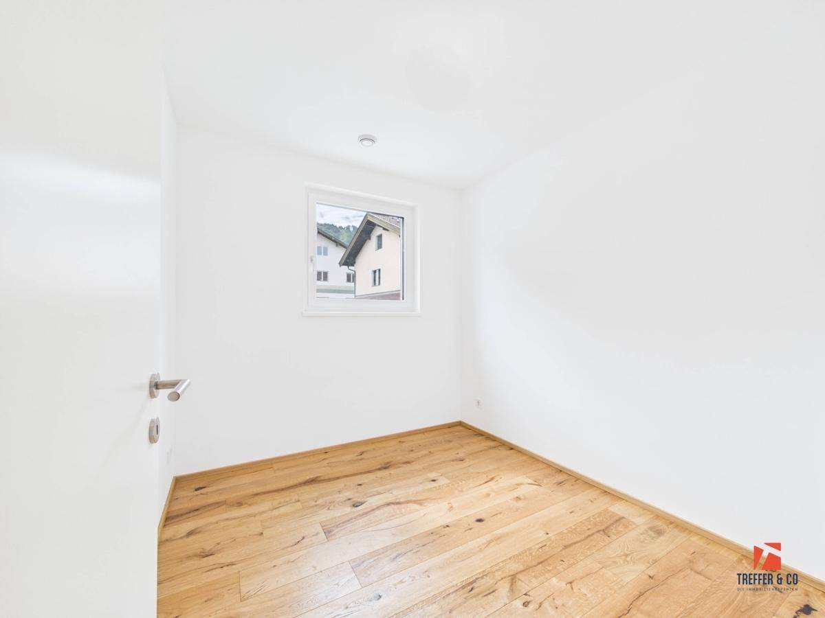 Kleines, helles Zimmer mit Holzboden und einem Fenster, ideal als Kinder- oder Gästezimmer.