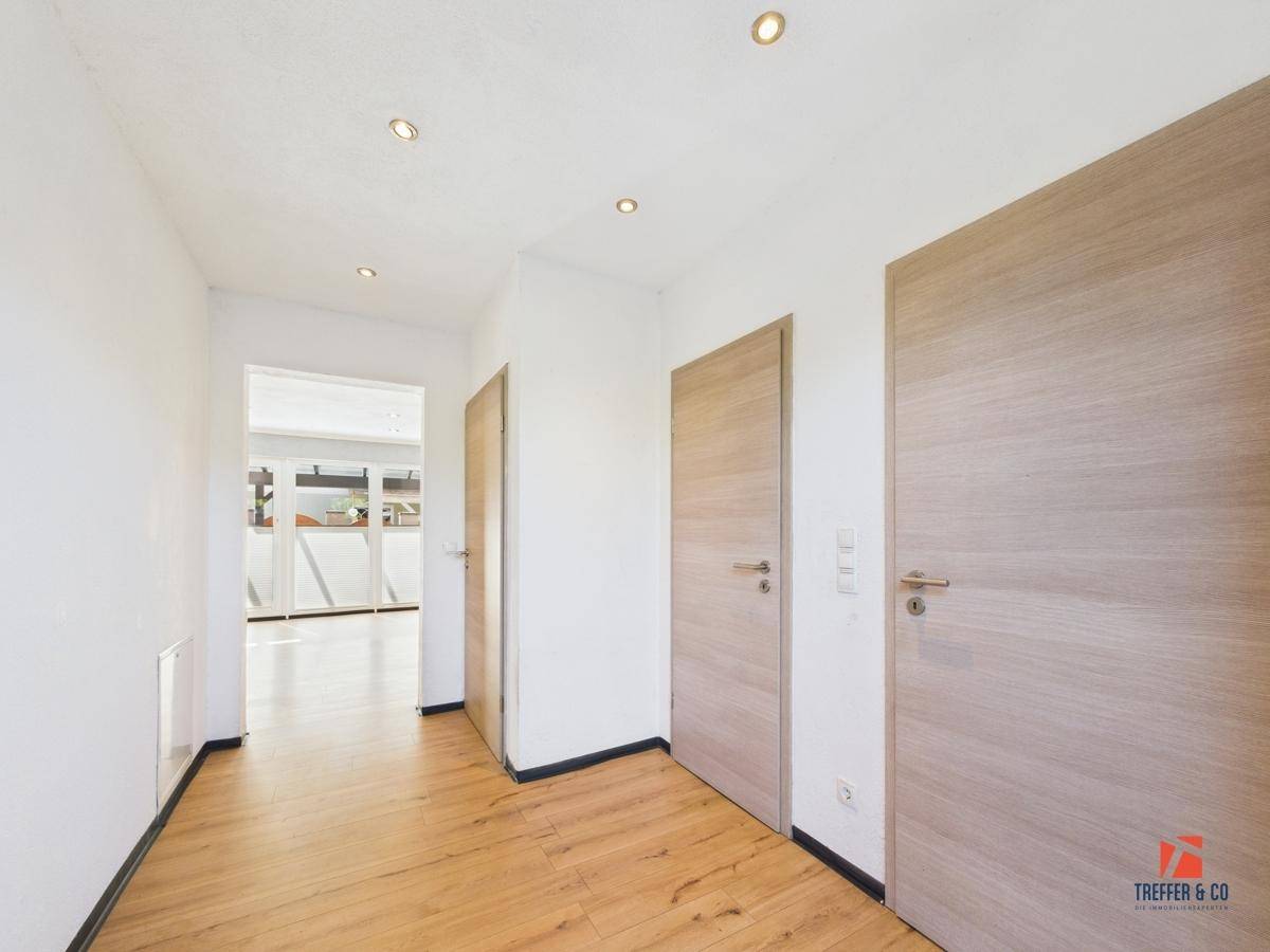 Heller Flur mit Laminatboden und mehreren Türen, die zu den Zimmern führen.