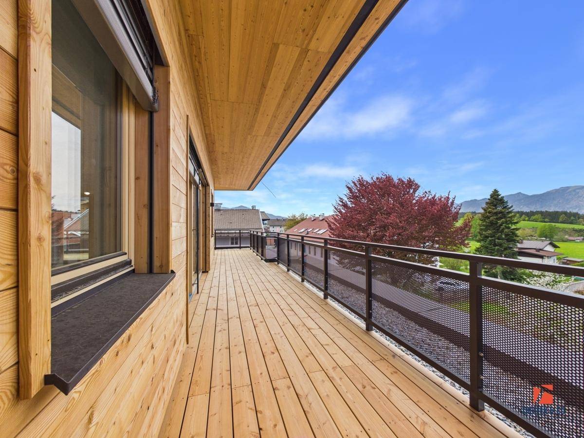 Geräumiger Holzbalkon mit Holzfassade und Blick auf die umliegende Berglandschaft.