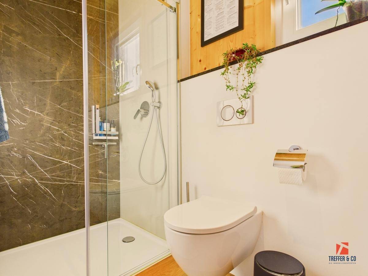 Helles Badezimmer mit moderner Dusche, wandhängendem WC und Holzdetails.