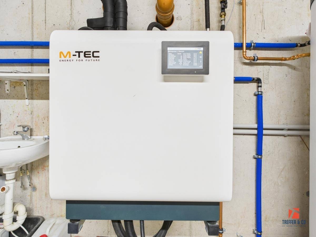 Heizungsanlage der Marke M-TEC im Technikraum mit sichtbaren Rohrleitungen.