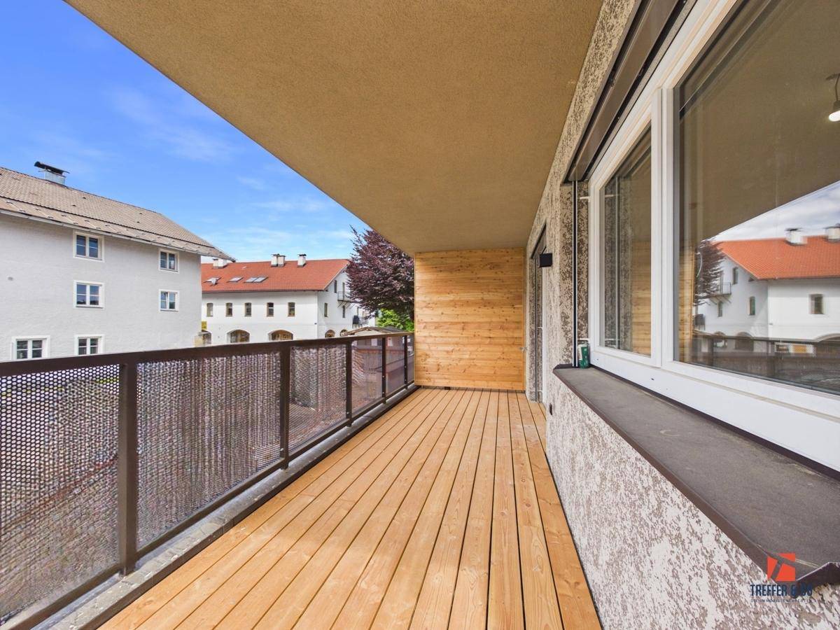 Langer Holzbalkon mit modernem Metallgeländer und Blick auf die Nachbarschaft.