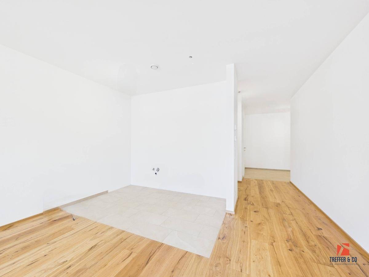 Leerer Raum mit Holzboden und einem gefliesten Bereich, ideal für eine offene Gestaltung.